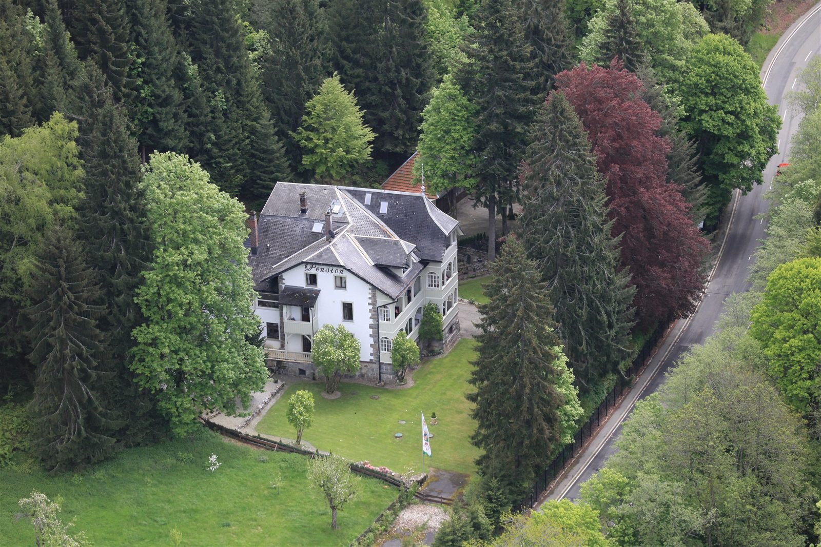 Luftbild der Villa Waldeck inmitten von Tannen und Laubbäumen